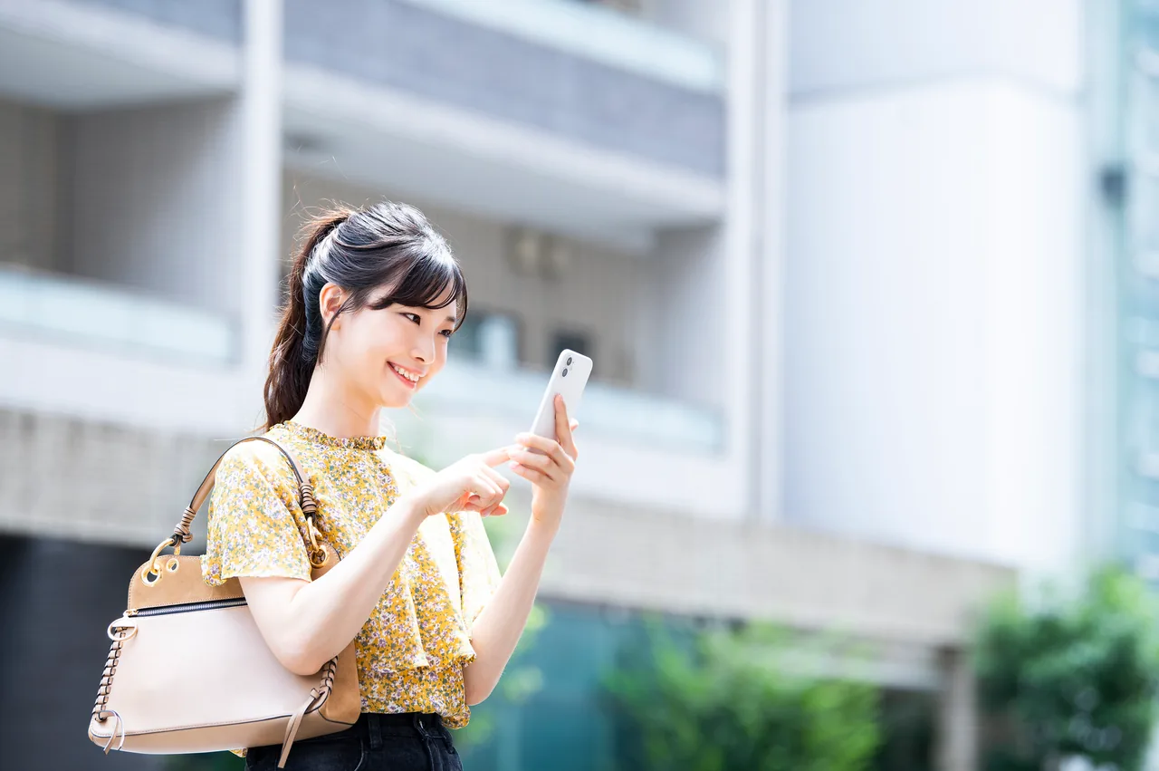 街なかでスマートフォンから近くの店を探す女性