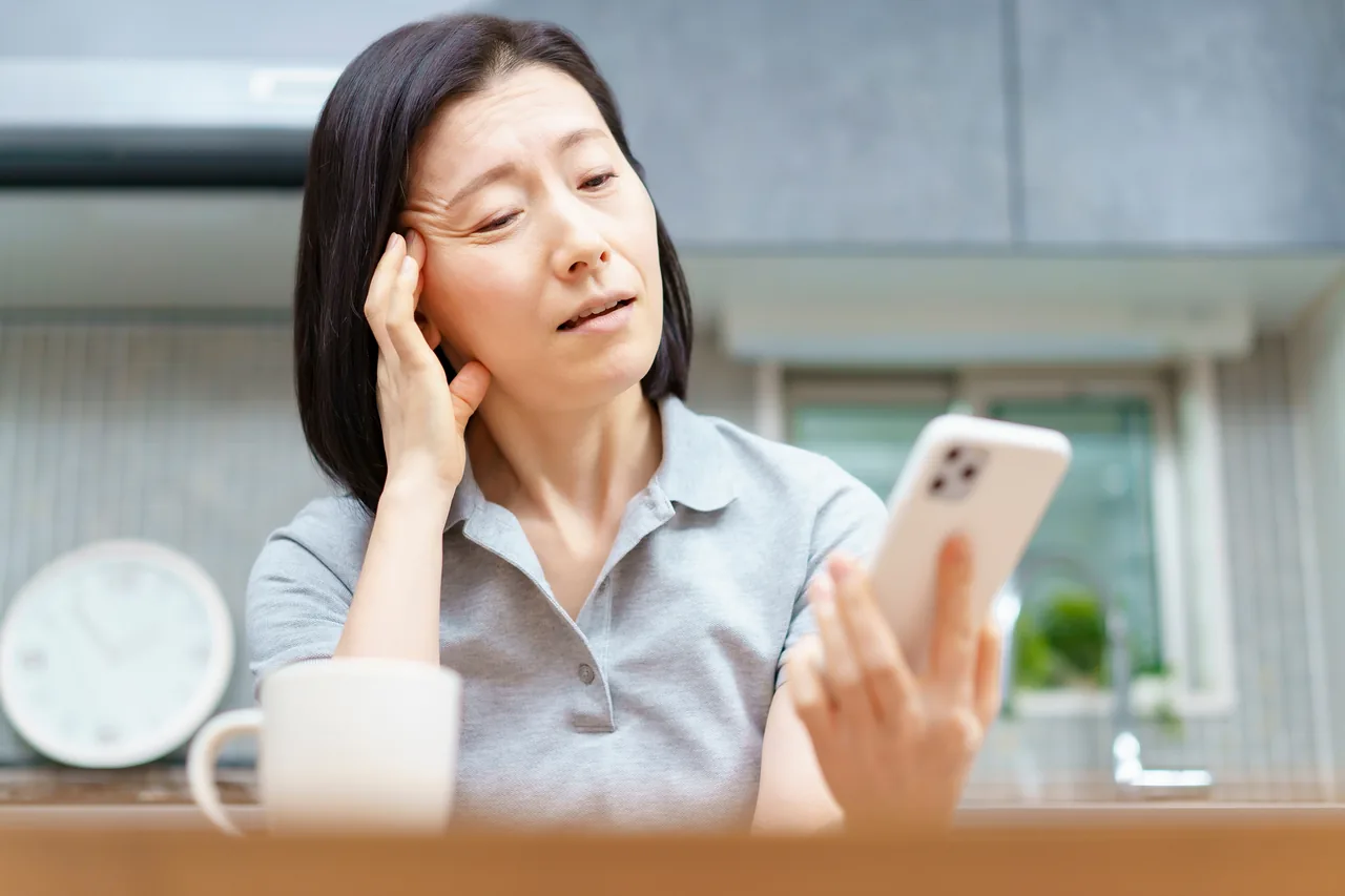 スマートフォンの予約画面を前に手が止まる女性